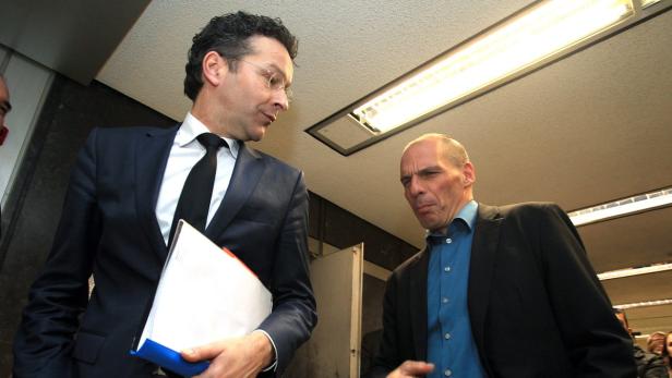 Zwei Männer in Anzügen stehen unter einer Neonröhre.