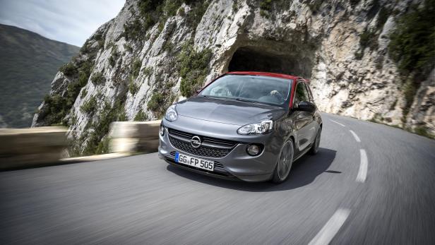 Ein grauer Opel Adam mit rotem Dach fährt auf einer kurvigen Bergstraße.