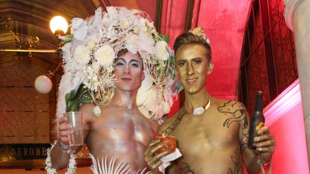 Zwei Männer, mit Körperbemalung und aufwendigen Kopfschmuck, posieren für ein Foto.