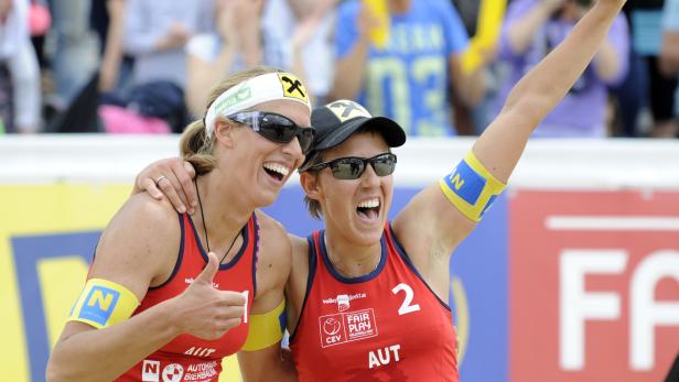Zwei Beachvolleyballspielerinnen jubeln über ihren Sieg.