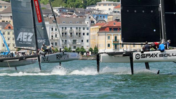 Zwei Tragflügelboote rasen auf dem Wasser vor einer Stadtkulisse.