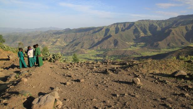 Eine Gruppe Kinder steht auf einem Hügel und blickt auf die grüne Landschaft Äthiopiens.