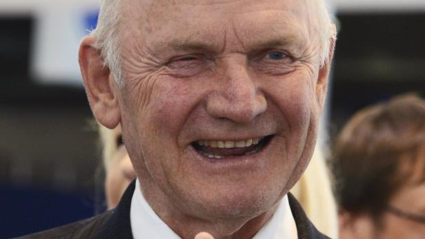 Ein älterer Mann blinzelt in die Kamera und lächelt.