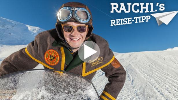Ein Mann mit Fliegerbrille und brauner Jacke fährt einen Bob auf einer schneebedeckten Piste hinunter.