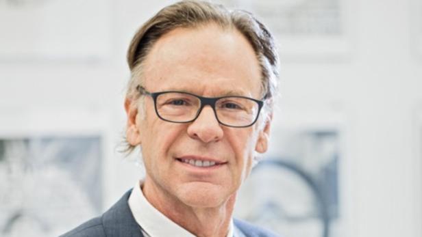 Ein Mann mit Brille und Anzug blickt in die Kamera.