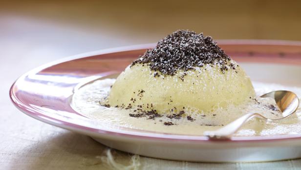 Ein Germknödel mit Mohn und Vanillesauce auf einem Teller.