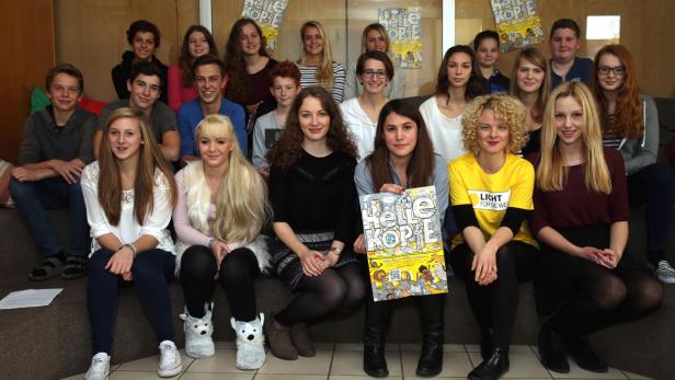 Eine Gruppe Jugendlicher sitzt mit dem Magazin „Helle Köpfe“ für ein Foto zusammen.