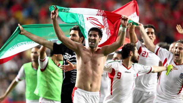 Eine Gruppe iranischer Fußballspieler feiert mit der iranischen Flagge.