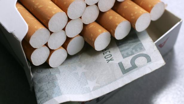 Eine geöffnete Zigarettenschachtel liegt auf einem Fünf-Euro-Schein.