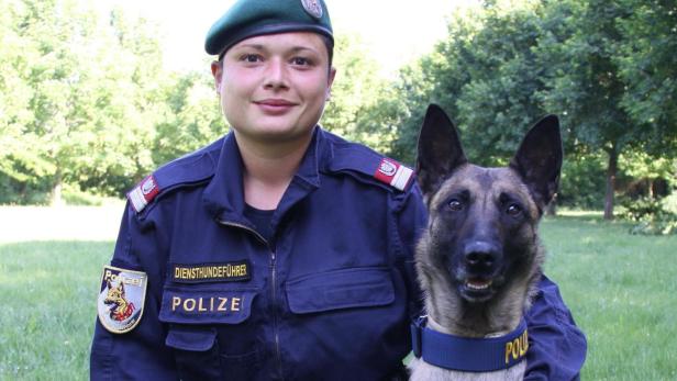 Eine Polizistin mit Diensthund im Grünen.