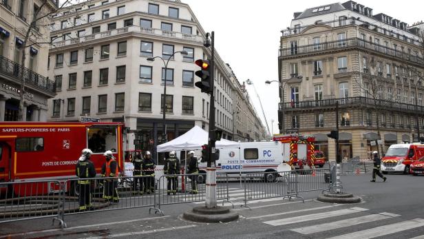 Feuerwehrleute und Einsatzfahrzeuge stehen auf einer Straße in Paris.