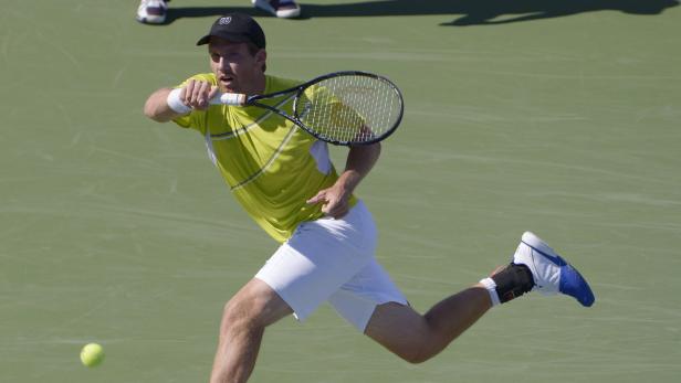 Ein Tennisspieler schlägt einen Ball auf einem Tennisplatz.