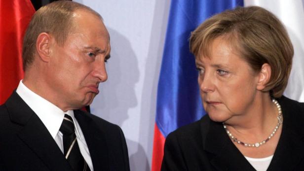 Wladimir Putin zieht eine Schmollmine, während Angela Merkel ihn ansieht.