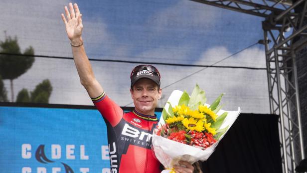 Cadel Evans winkt mit einem Blumenstrauß in der Hand.
