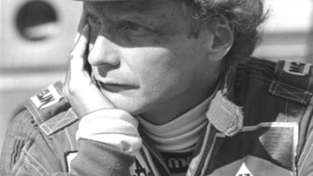 Niki Lauda in Rennfahrerkluft mit Marlboro-Logo und nachdenklichem Gesichtsausdruck.