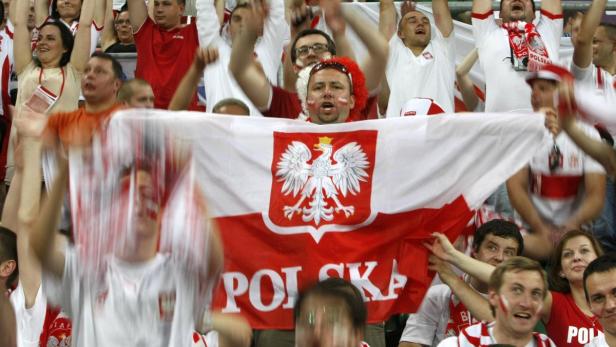 Polnische Fans jubeln mit einer großen polnischen Flagge.