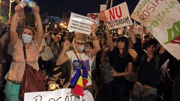 Eine Menschenmenge demonstriert mit Schildern gegen ein Referendum in Roșia Montană.