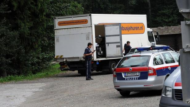 Polizisten untersuchen einen Lieferwagen, in dem sich ein Motorrad befindet.