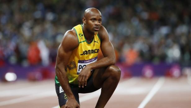 Asafa Powell, ein jamaikanischer Sprinter, kniet auf einer Laufbahn.