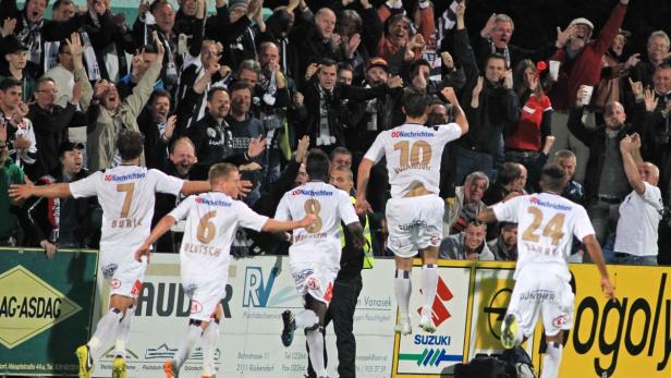 Fußballspieler jubeln vor einer jubelnden Zuschauermenge.