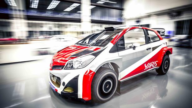 Ein rot-weiß lackierter Toyota Yaris Rallye-Wagen in einer Werkshalle.