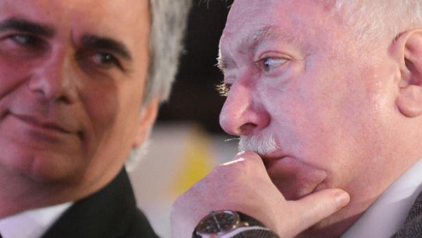 Zwei Männer, einer mit grauem Haar, der andere mit weißem Schnurrbart, im Gespräch.