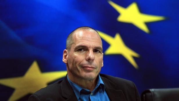Porträt von Yanis Varoufakis vor der Flagge der Europäischen Union.