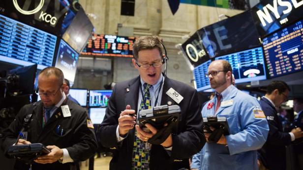 Händler arbeiten an der New Yorker Börse vor Anzeigetafeln.