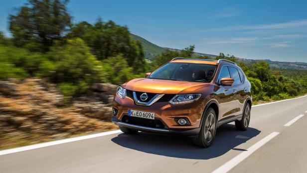 Ein bronzefarbener Nissan X-Trail fährt auf einer Landstraße.