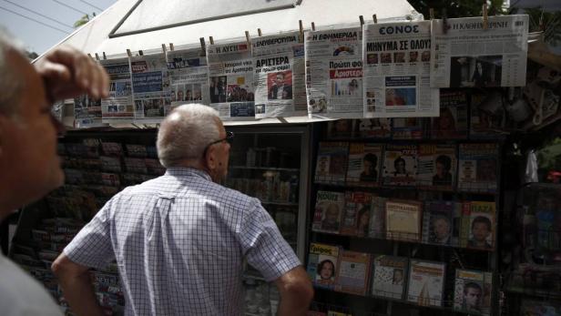 Zwei Männer stehen vor einem Kiosk mit Zeitungen und Zeitschriften.