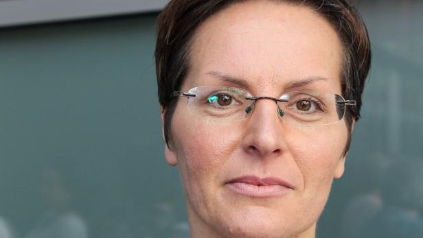 Nahaufnahme einer Frau mit Brille und kurzen, dunklen Haaren.