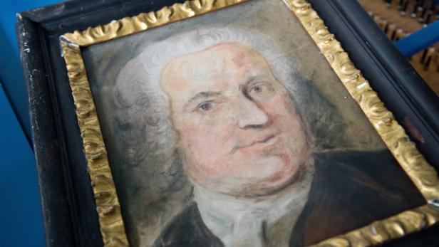 Ein Porträt eines Mannes mit weißer Perücke in einem verzierten Rahmen.