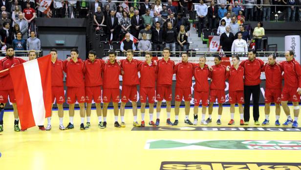 Die österreichische Handballnationalmannschaft steht mit der rot-weiß-roten Flagge auf dem Spielfeld.