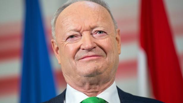 Porträt von Heinz Fischer vor blau-roten Flaggen.