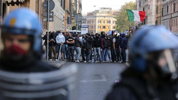 Polizisten stehen vor einer Menschenmenge mit italienischer Flagge.