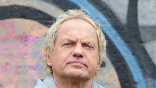Ein Porträt von Hugo Egon Balder vor einer Wand mit Graffiti.