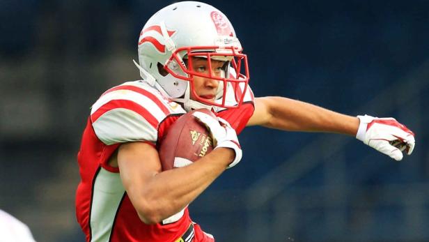 Ein American-Football-Spieler in roter und weißer Uniform mit einem Football in der Hand.