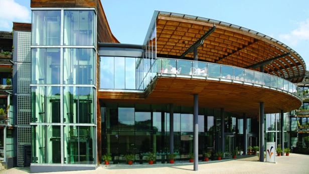 Ein modernes, geschwungenes Gebäude mit viel Glas und Holzelementen.