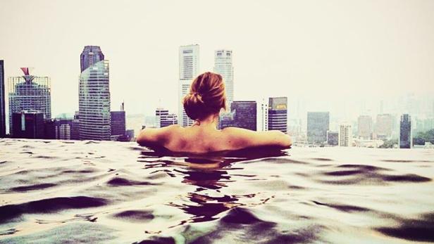 Eine Frau schwimmt in einem Pool mit Blick auf die Skyline der Stadt.