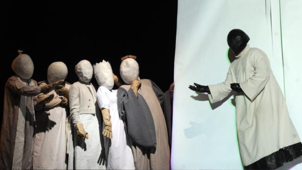 Eine Gruppe von Personen in Kostümen und Masken auf einer Bühne.