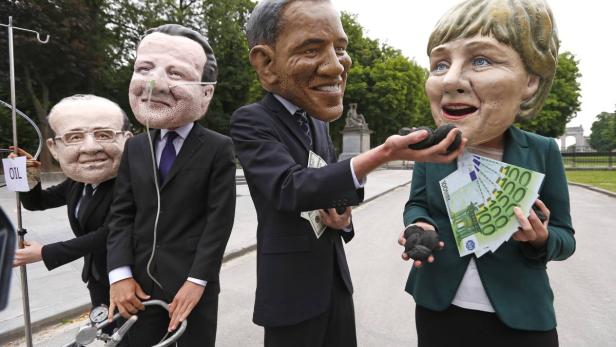 Oxfam-Aktivisten während einer Protestaktion gegen den Gipfel mit den Masken von Francois Hollande, David Cameron, Barack Obama und Angela Merkel.
