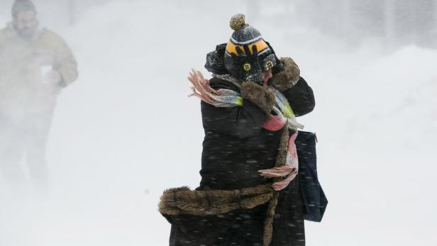 A woman holds onto her hat against the wind during