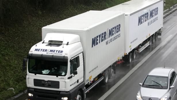 Ein Lastwagen der Spedition Meyer & Meyer fährt auf einer regnerischen Straße.