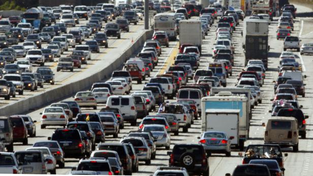 Stau auf einer mehrspurigen Autobahn mit vielen Autos und Lastwagen.