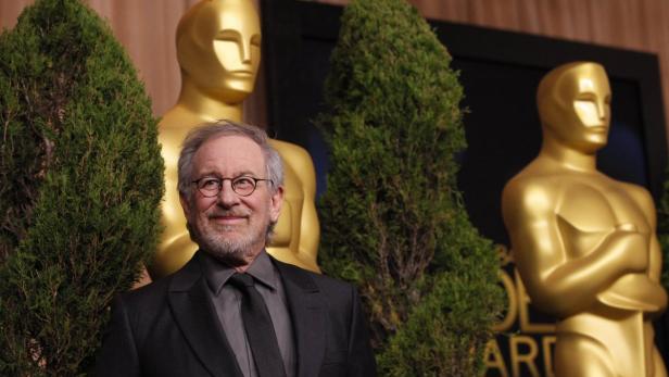 Steven Spielberg posiert vor Oscar-Statuen.