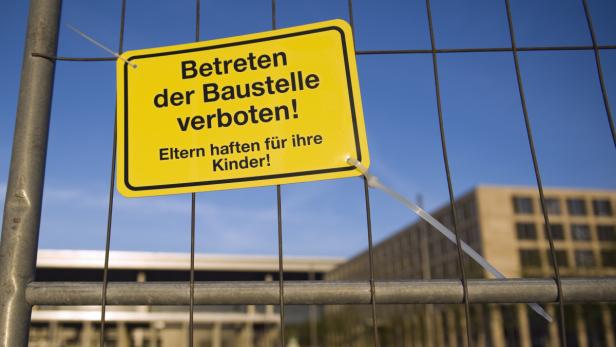 Ein gelbes Schild an einem Bauzaun warnt: „Betreten der Baustelle verboten! Eltern haften für ihre Kinder!“.