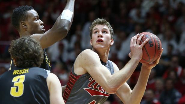 Ein Basketballspieler mit Ball im Spiel, umgeben von anderen Spielern.