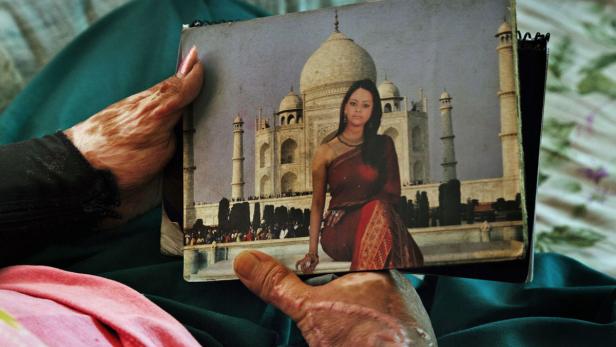 Eine Person hält ein Foto von einer Frau vor dem Taj Mahal.