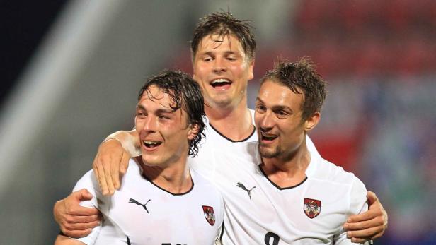 Drei österreichische Fußballspieler in weißen Trikots feiern gemeinsam.
