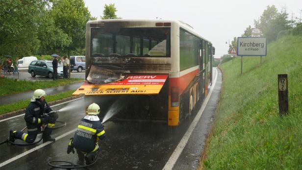 Feuerwehrleute löschen einen ausgebrannten Bus in Kirchberg an der Raab.
